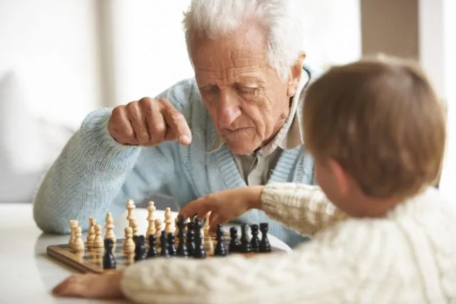 elderly-man-teaches-grandson-about-chess