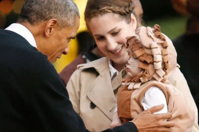 Obama greets a toddler in a lion costume while receiving children on the South Lawn for a Halloween trick-or-treating celebration at the White House in Washington