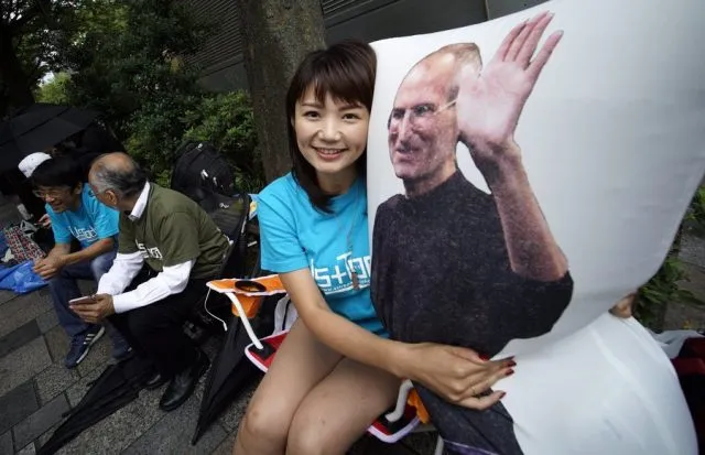 epa05541641 Apple enthusiast Ayano Tominaga poses with a pillow bearing an image of Apple co-founder Steve Jobs after she bought the new iPhone 7 at the Apple Store of Omotesando shopping district in Tokyo, Japan, 16 September 2016. Tominaga and other Apple fans were lined up for two days before the store to be the first to buy Apple's new smartphones.  EPA/FRANCK ROBICHON